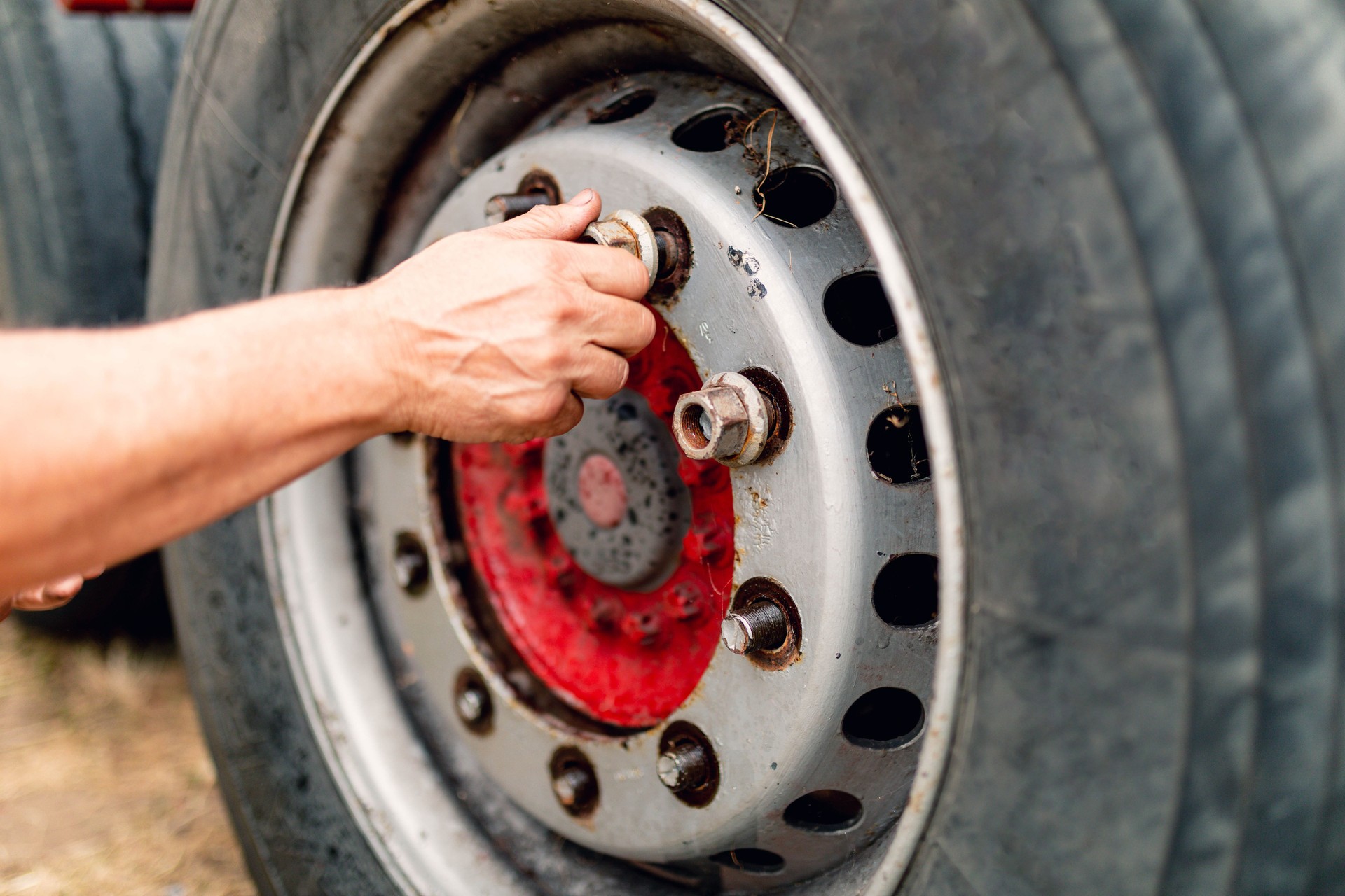 The close-up picture of a man's hand screwing wheel bolts.